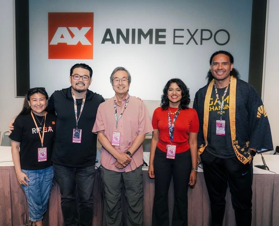 Photograph of the staff members from CAPE as they stand in front of an Anime Expo display